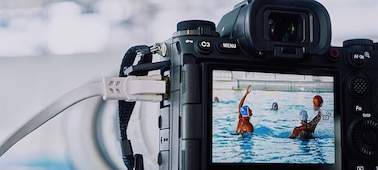 Imagen de uso de la cámara montada en un trípode y conectada a un cable LAN que hace capturas a un partido de waterpolo con una imagen en vivo que se muestra en el monitor LCD