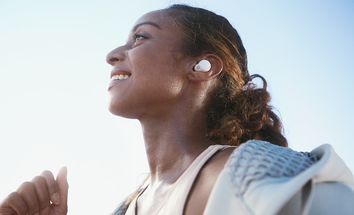 Primer plano de cabeza y hombros de una mujer trotando con LinkBuds S blancos